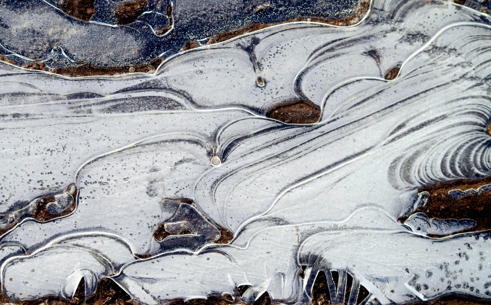 Aerial view of frozen agricultural soil and salt ponds or evaporation beds with geometric patterns of white salt-crusted surfaces, brown soil, and crystalline formations in a winter landscape.