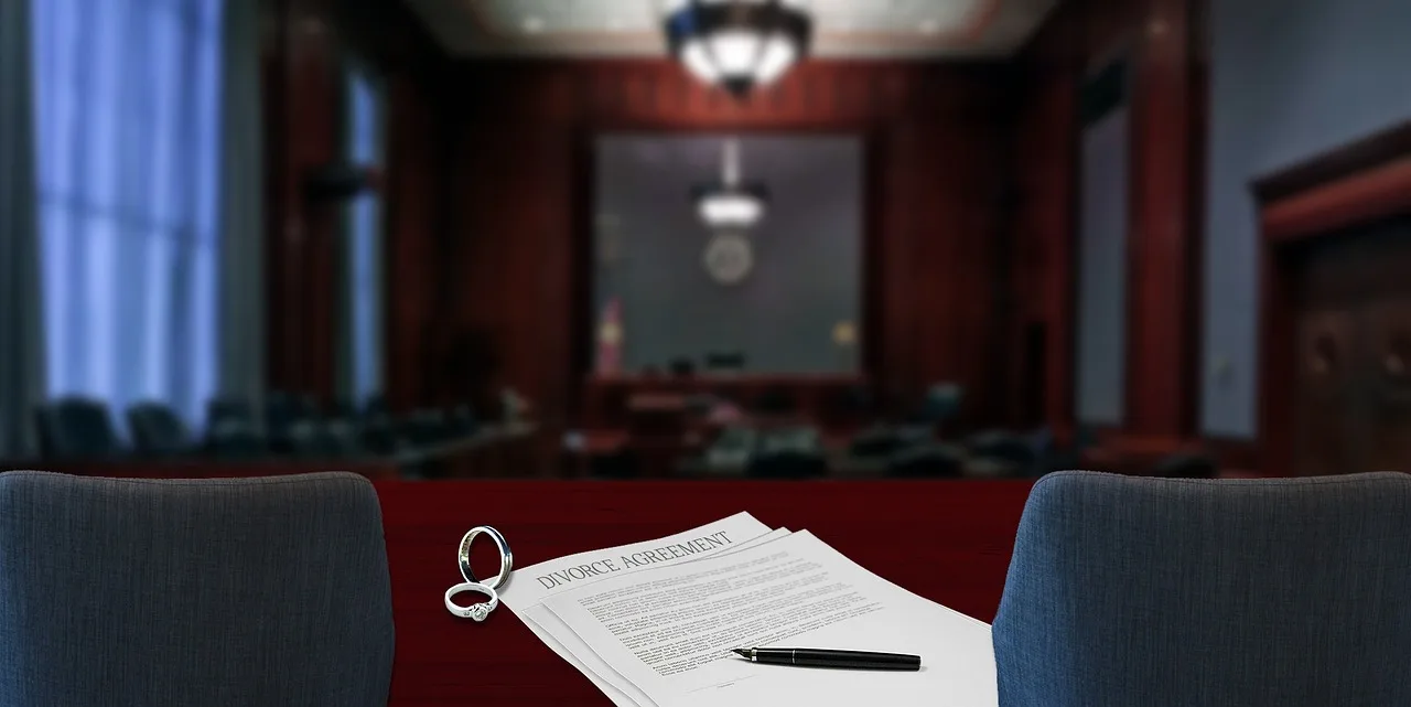 A modern conference room with a dark wood table, a presentation screen visible in the background, and professional lighting from above, with what appears to be a single document or folder visible on the table surface.