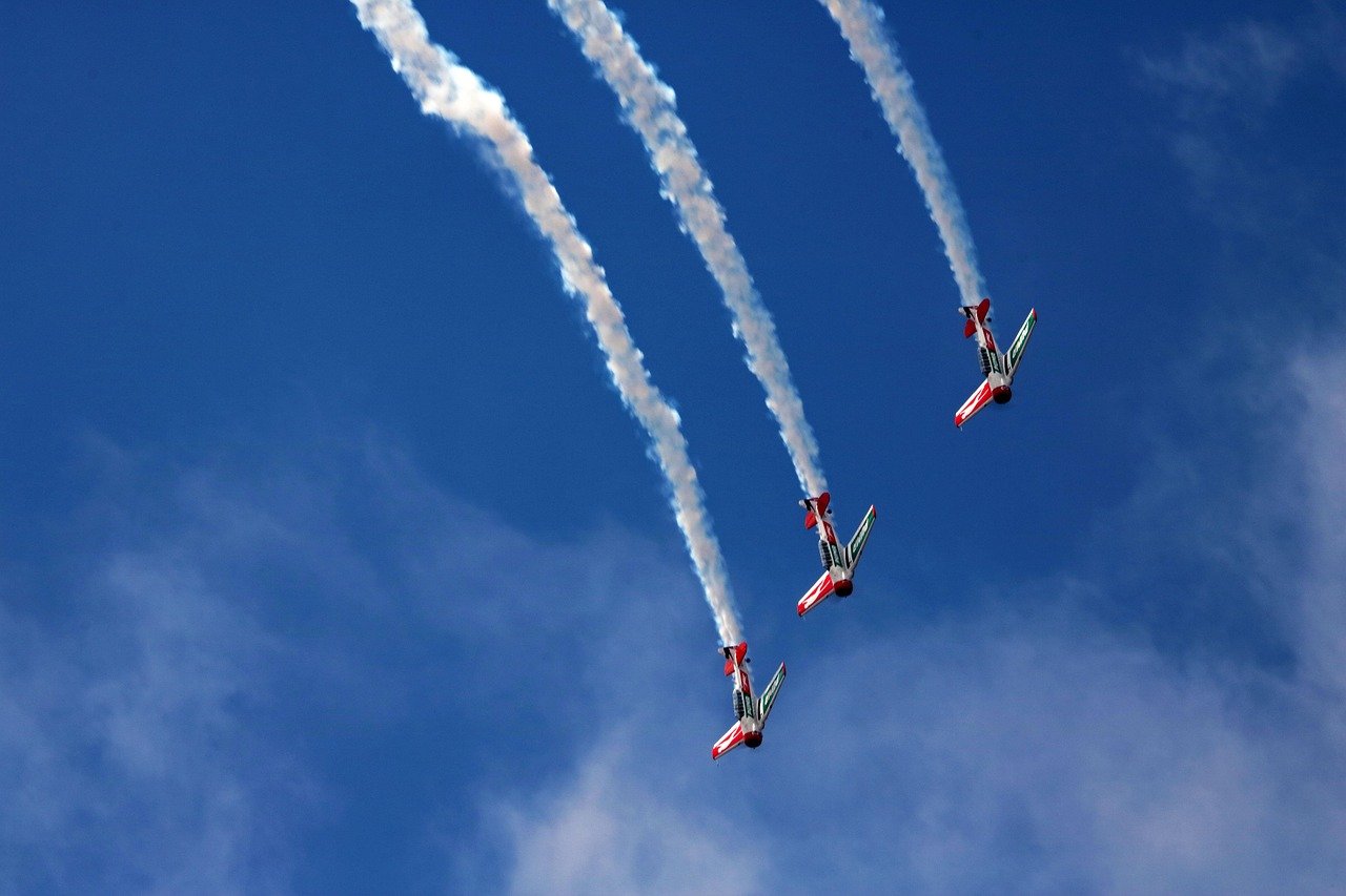 Two aircraft contrails streaking across a deep blue sky, creating white parallel trails from high-altitude jet aircraft.