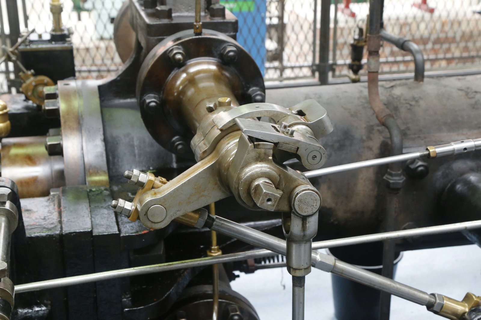 A close-up view of a materials testing machine with mechanical loading apparatus applying force to a metal specimen with honeycomb or lattice structure in a laboratory setting, showing hydraulic or mechanical components and metal framework.